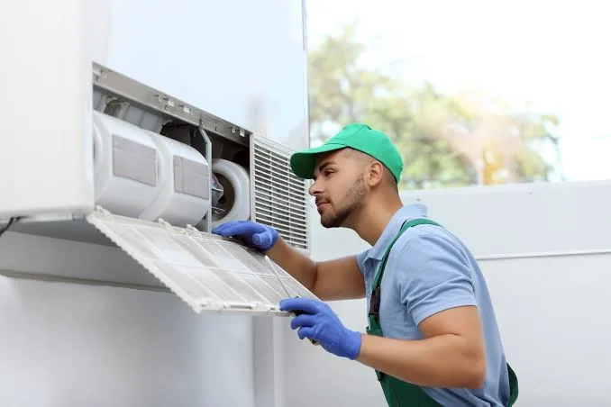 Technician inspecting an indoor air conditioning unit
