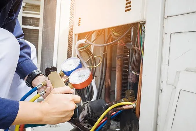 HVAC technician using pressure gauges during system diagnostics