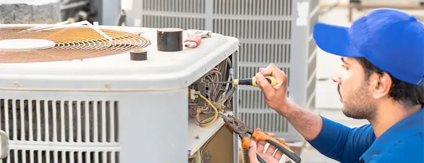 Technician working on an outdoor air conditioning condenser