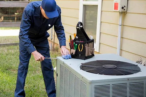 Technician performing routine service on an outdoor HVAC unit