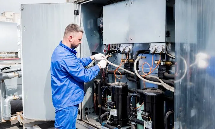 Technician evaluating components inside a large HVAC system